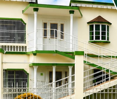 The Eazi Days home — a cream and green two-storey house with white railings and a garden at Frenchman Heights