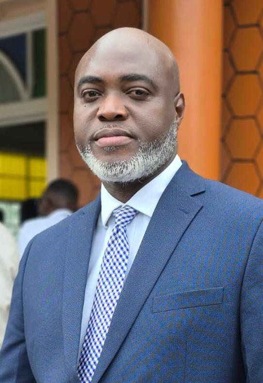 Portrait of Marlon Moore in a navy blue suit and checked tie
